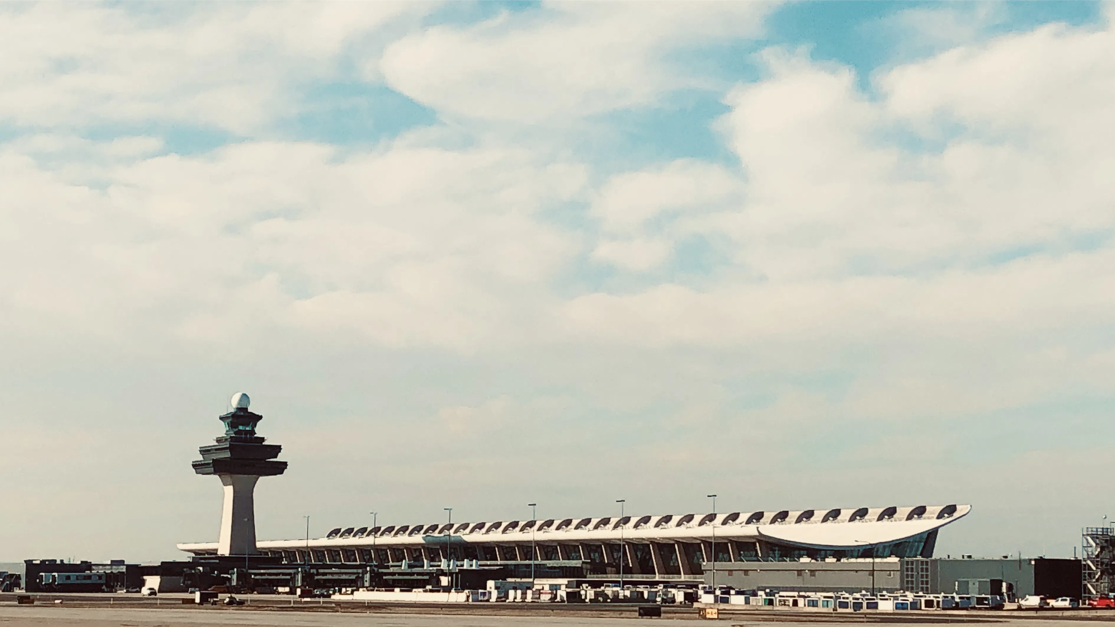 An airport terminal and control tower beneath a broad sky