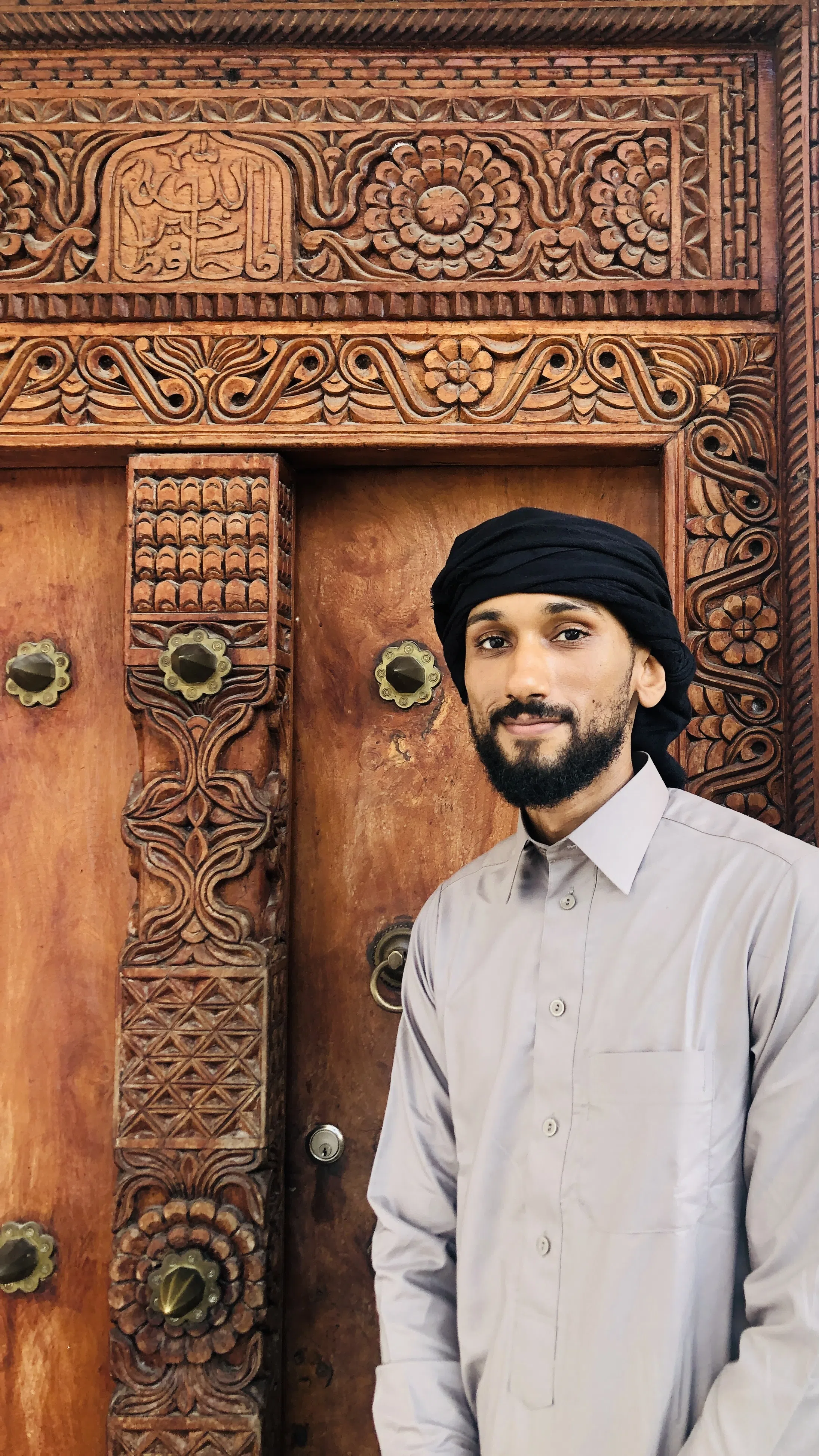 A man standing before an ornate carved wooden doorway