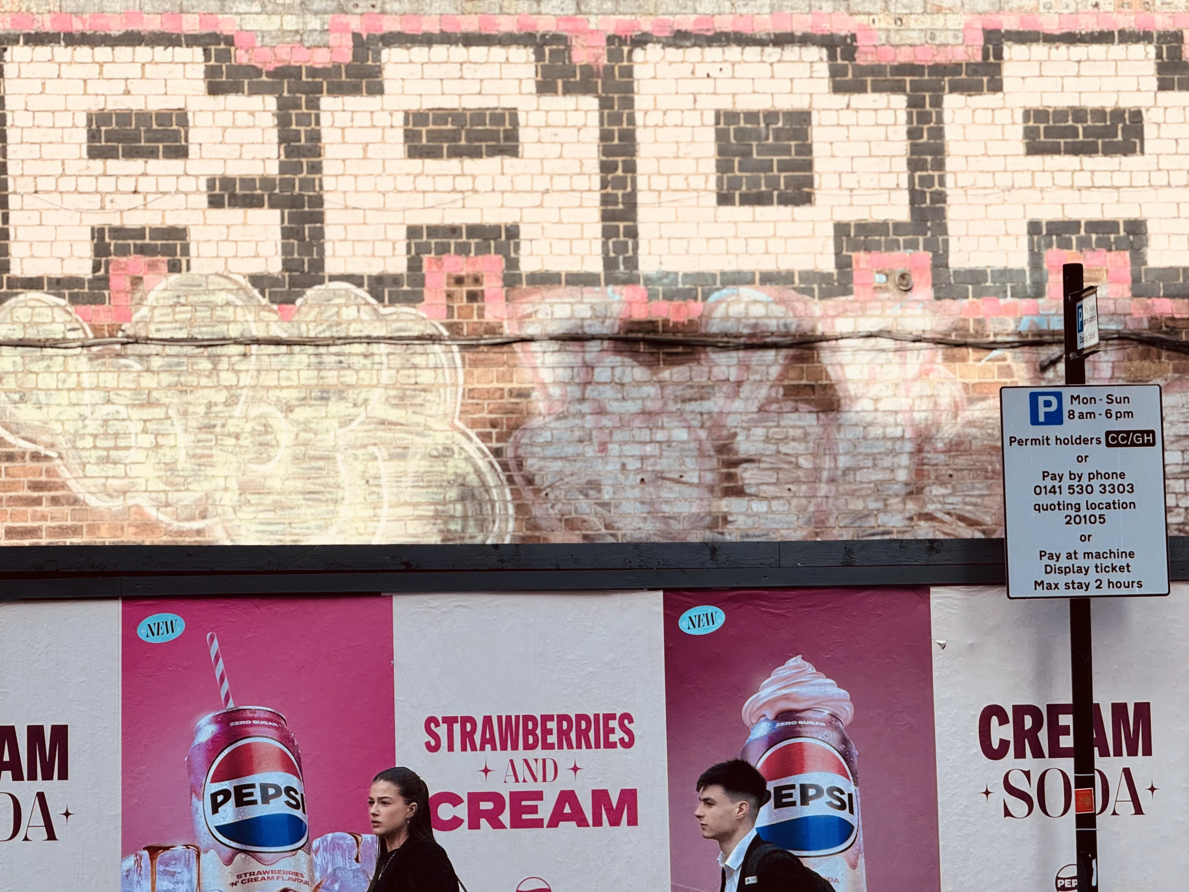 Bright storefront graphics and pedestrians against an urban brick wall