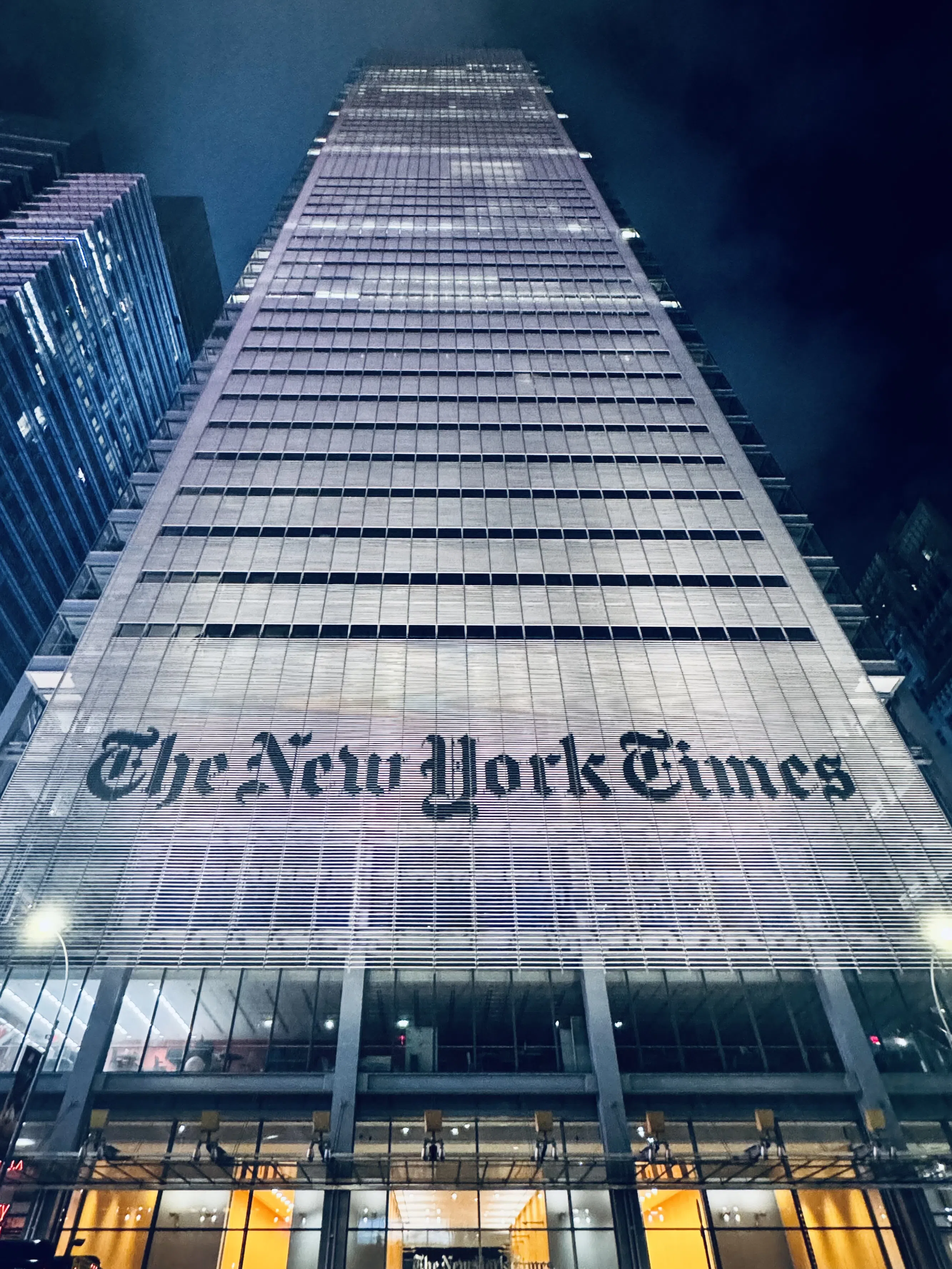 A dramatic upward view of a tall city building at night