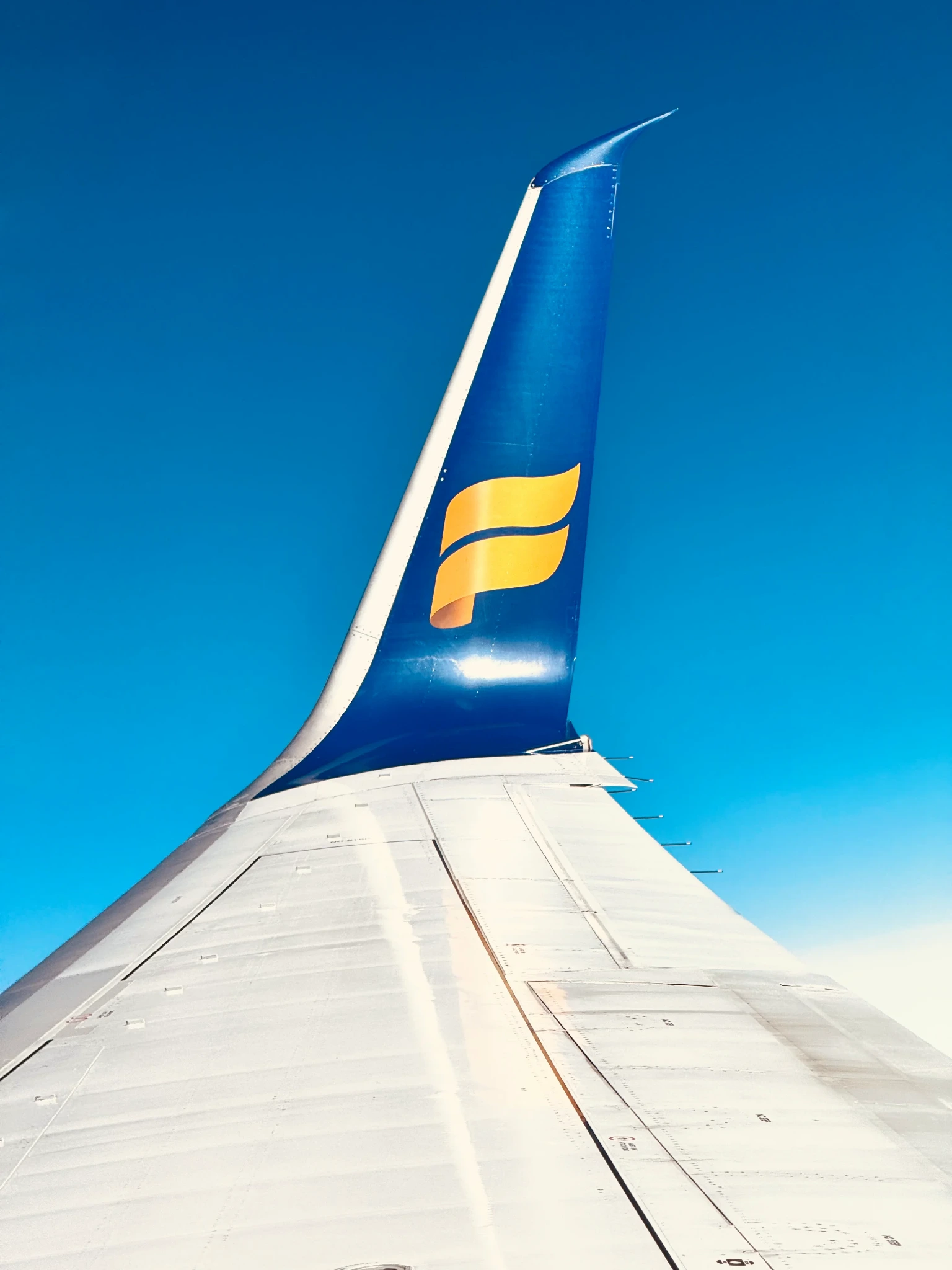 An Icelandair wing and tail against a vivid blue sky