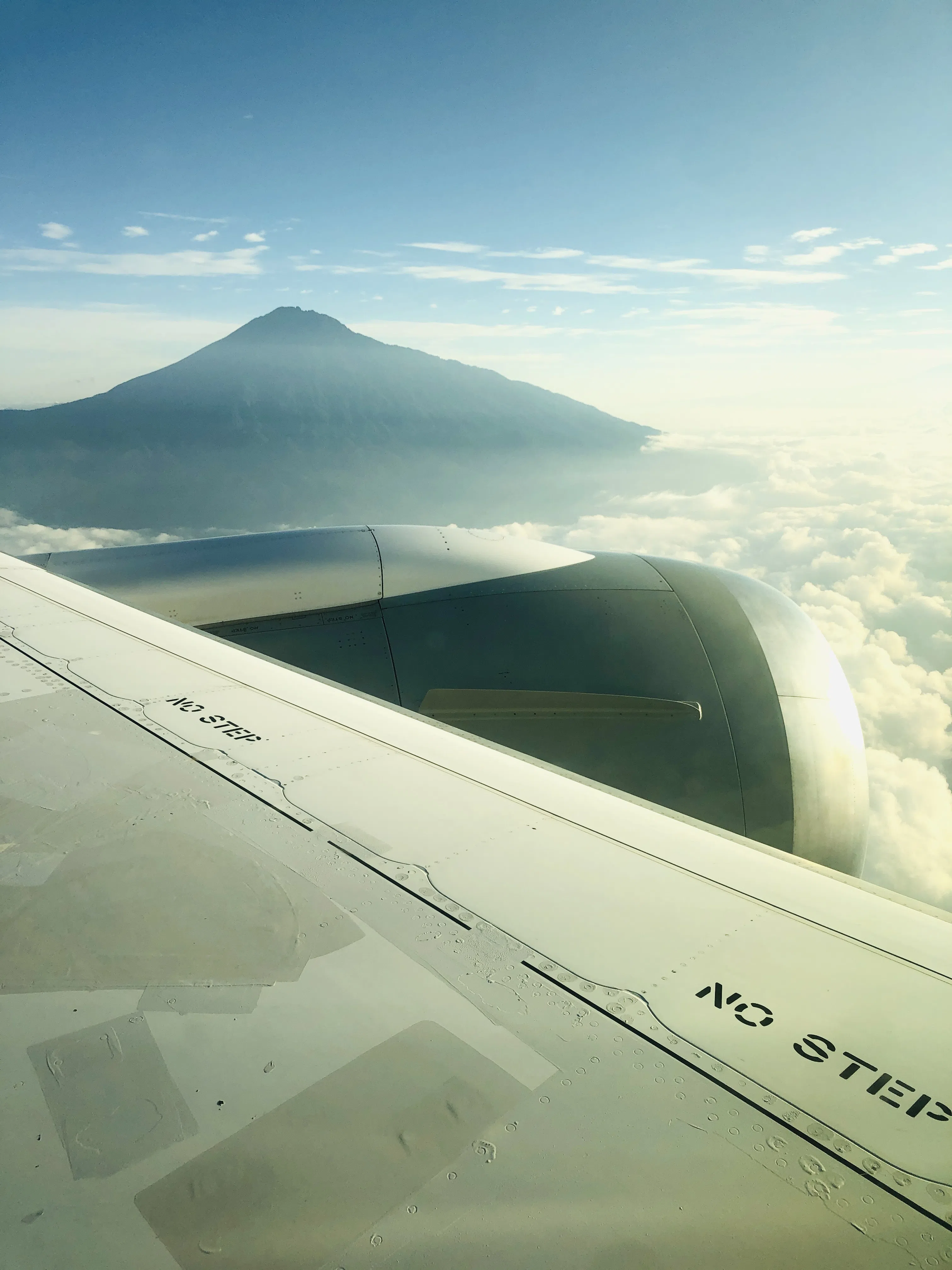 View from an airplane wing toward a mountain above the clouds