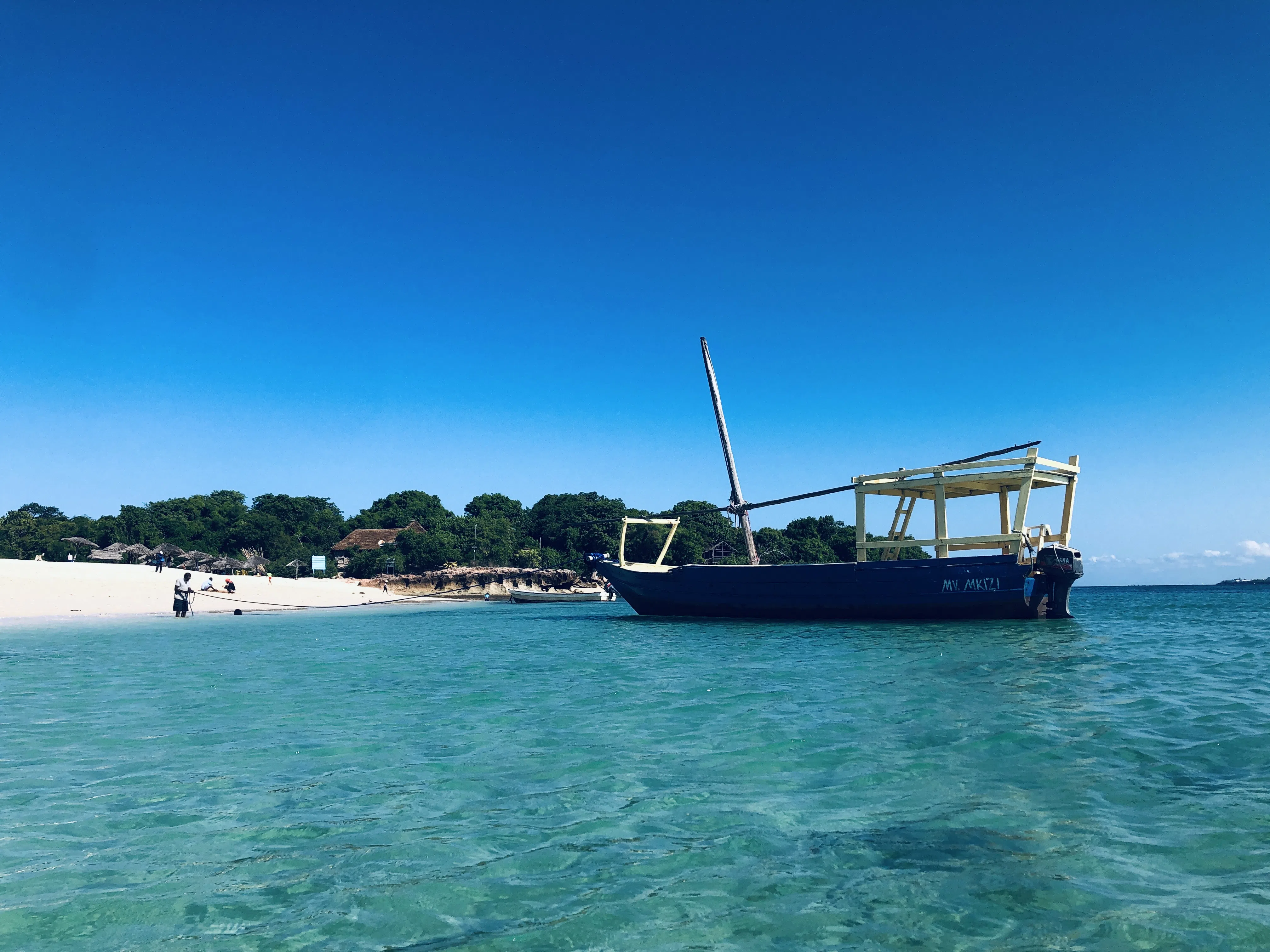A small boat floating on clear blue coastal water