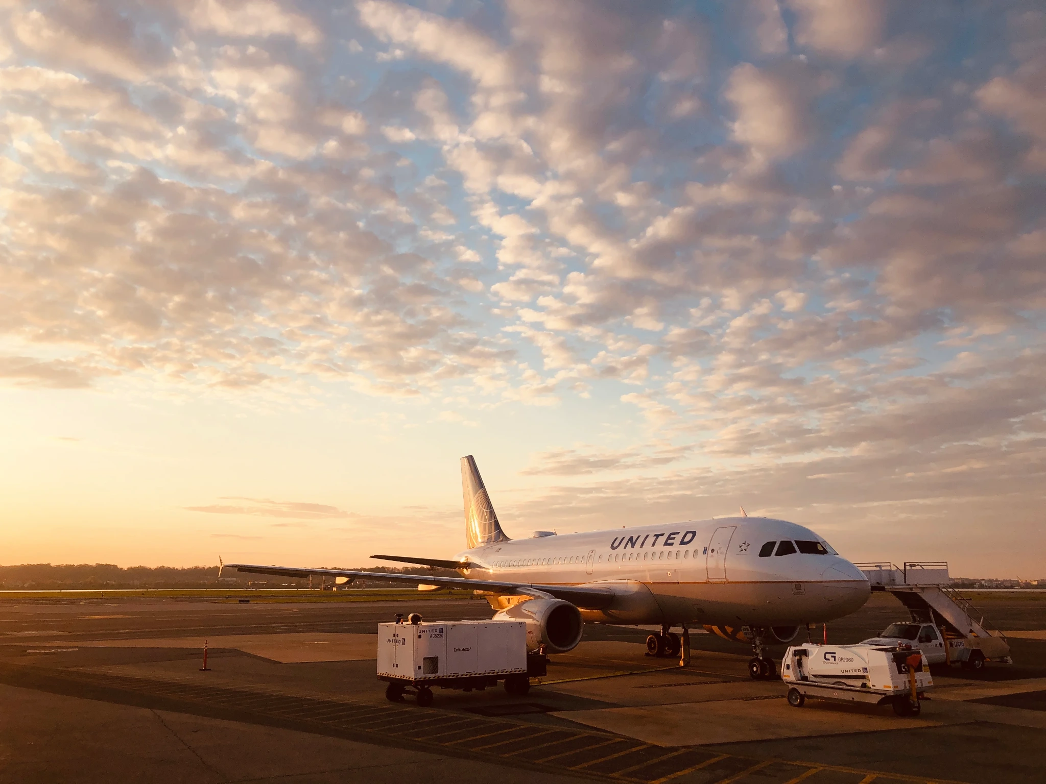 A United Airlines aircraft being serviced on the ramp at sunset