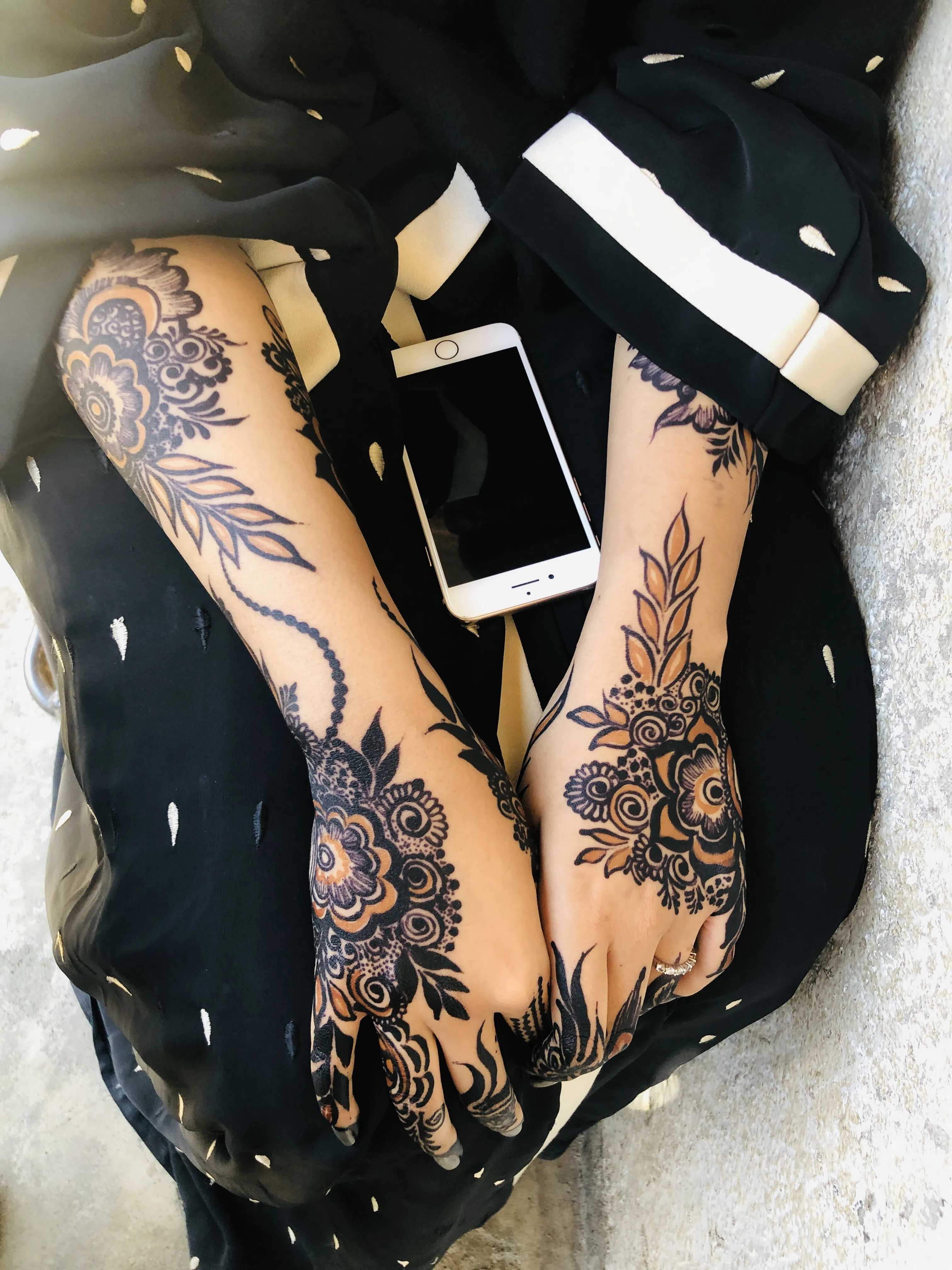 Tattooed forearms and hands resting together