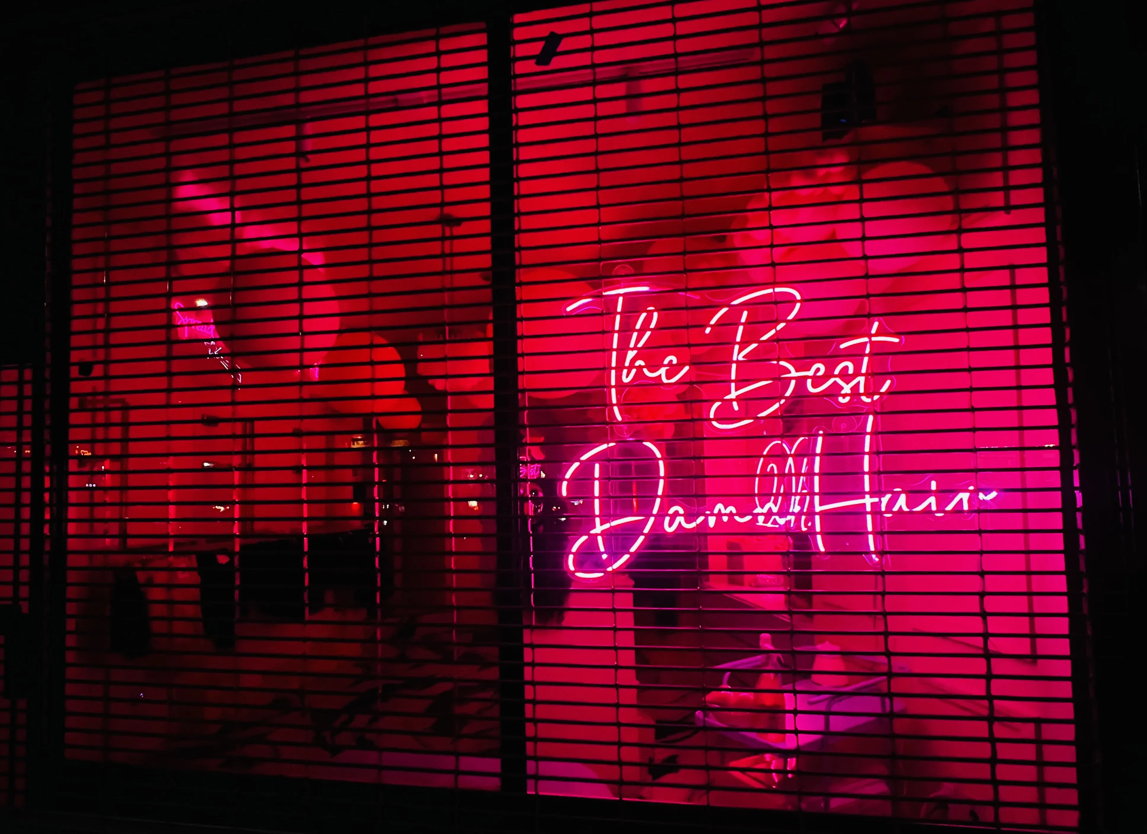 A vivid neon sign glowing through a dark storefront window