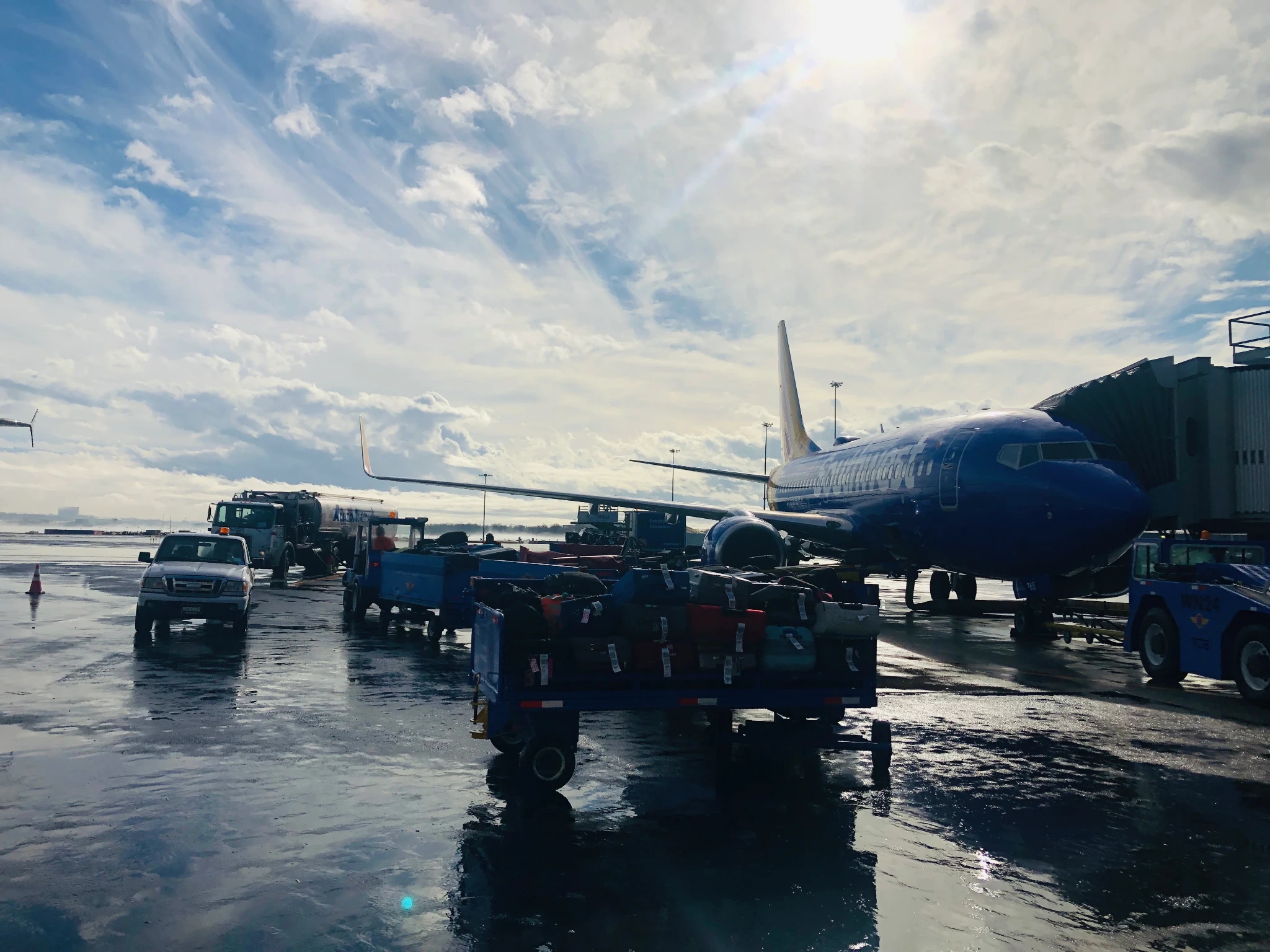 Ground crews, baggage carts and aircraft arranged across a busy airport ramp