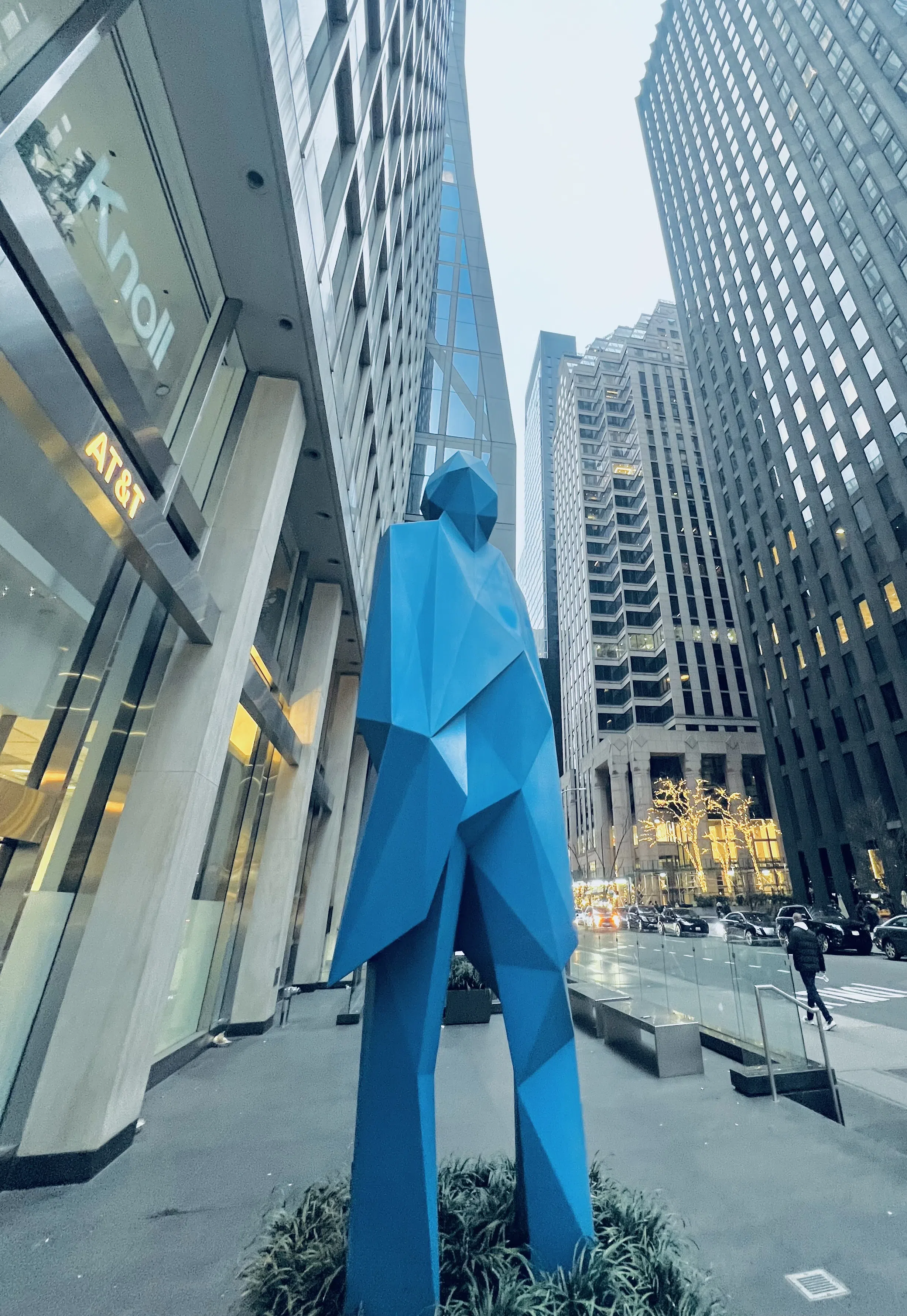 A blue geometric street sculpture framed by tall city buildings